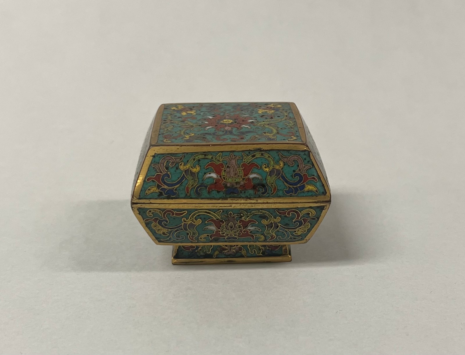 Covered cloisonné box with floral ornament, angled sides and a small foot