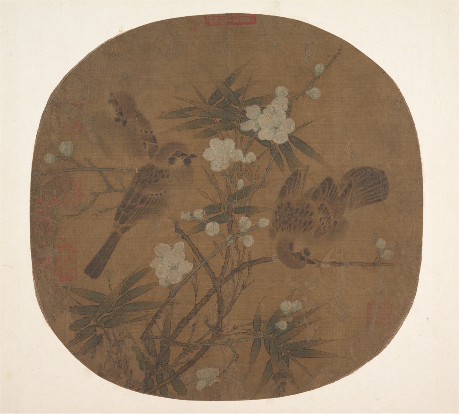 Three sparrows turn in different directions among pale plum blossoms and dark bamboo leaves within a rounded silk painting.