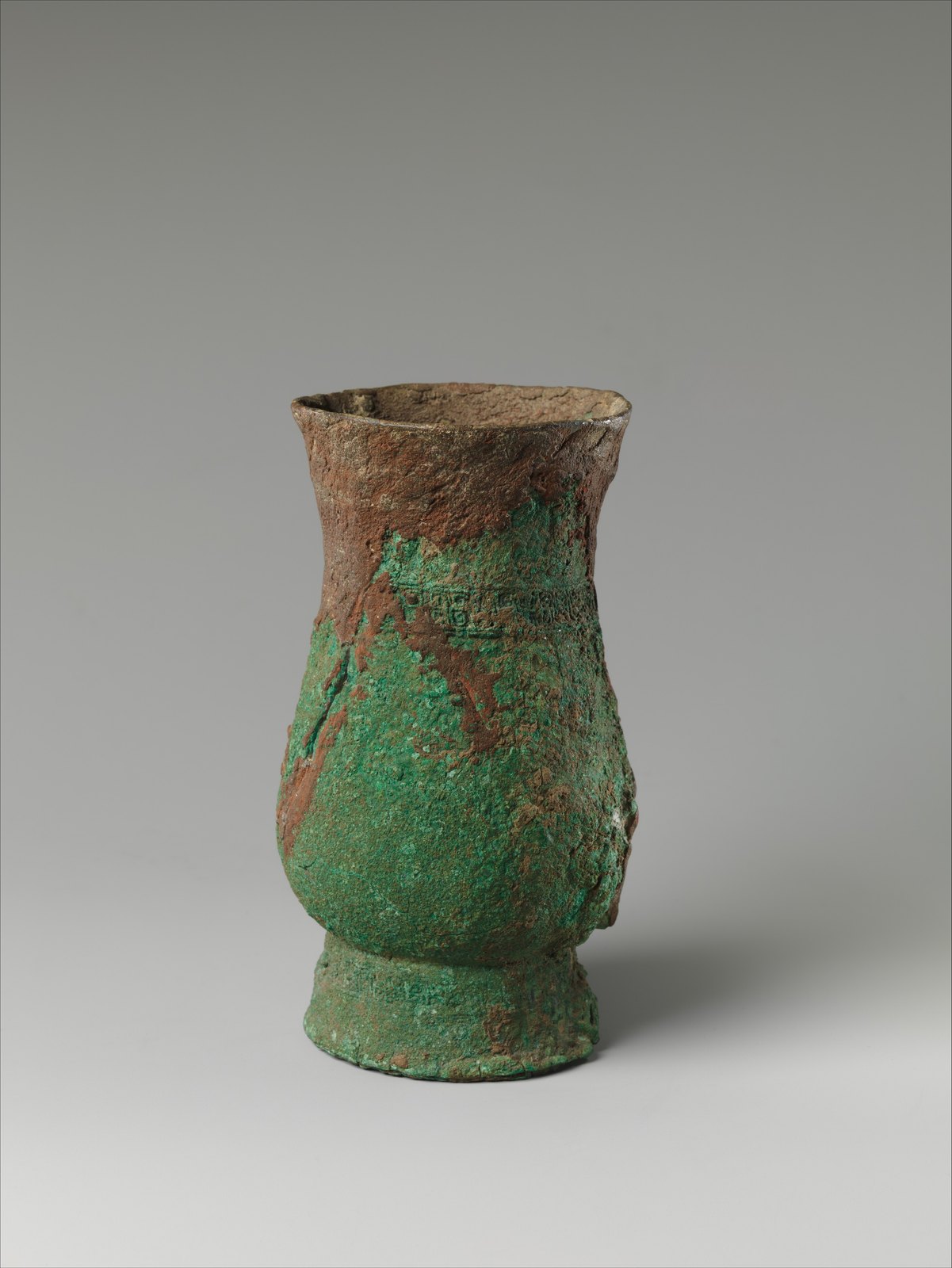 Small bronze zhi cup with a rounded lower body, gently flared rim and uneven green and brown surface