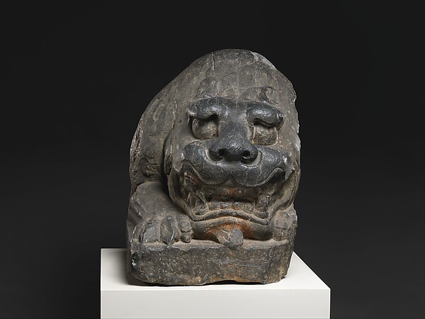 A sixth-century limestone guardian lion crouches with its head raised.