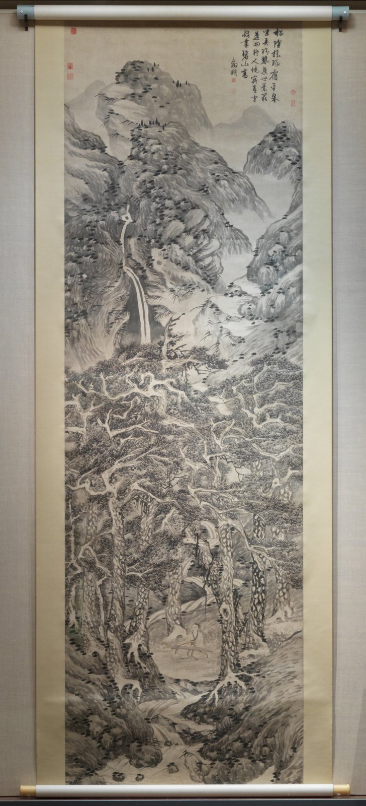 Tall ink landscape with pine trees and a small figure playing a zither.