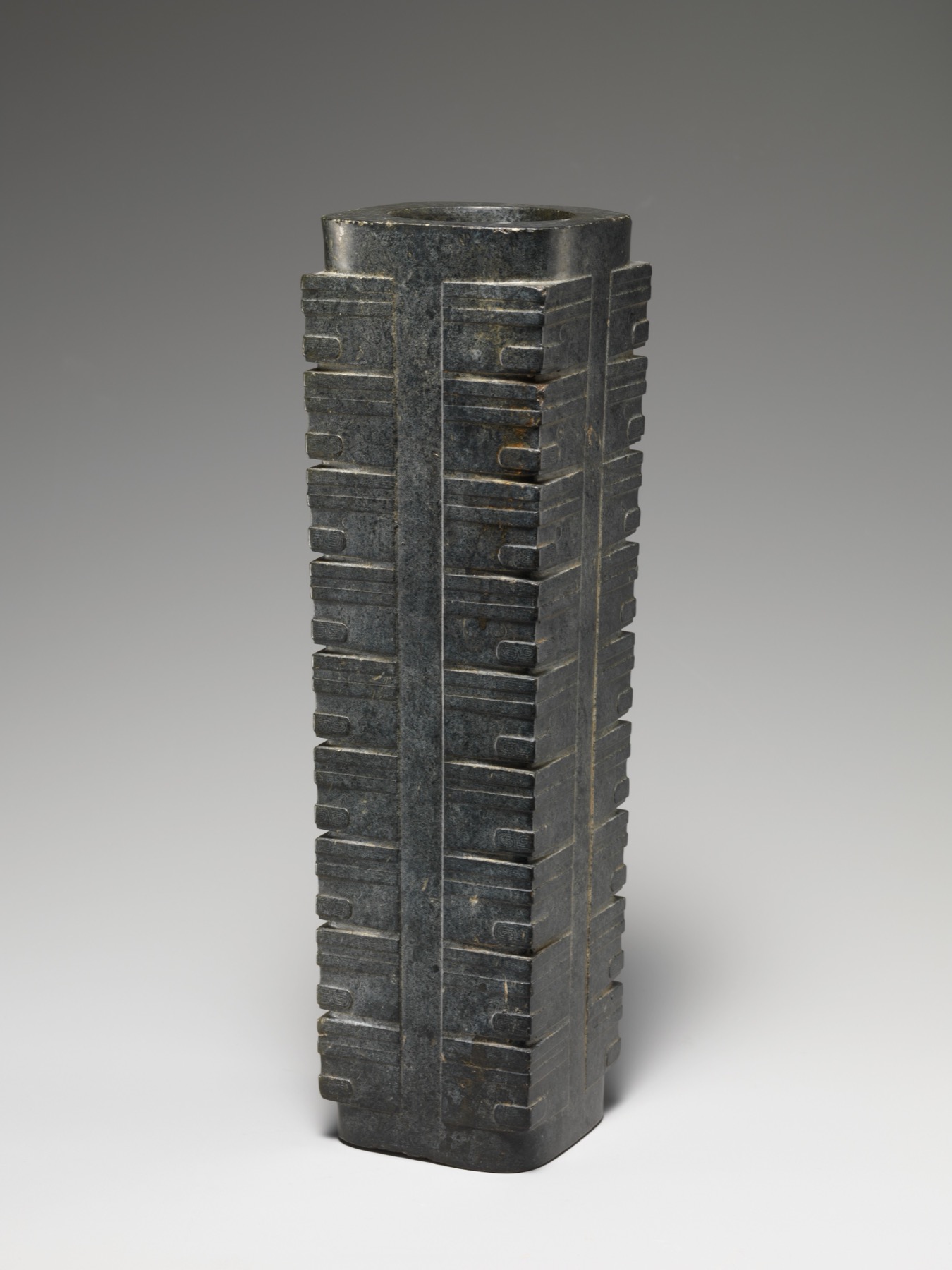 A Neolithic jade cong joins a circular inner bore to a squared exterior.