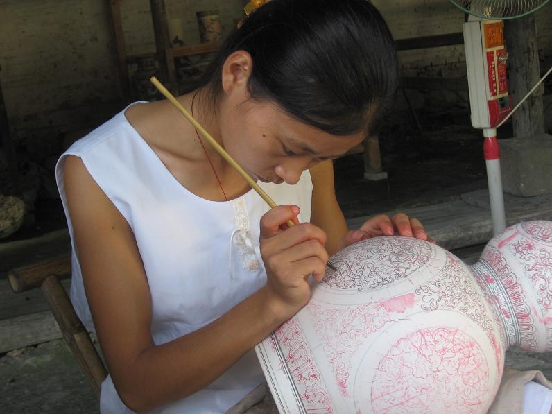 Ceramic workers shaping and finishing porcelain inside a Jingdezhen workshop.