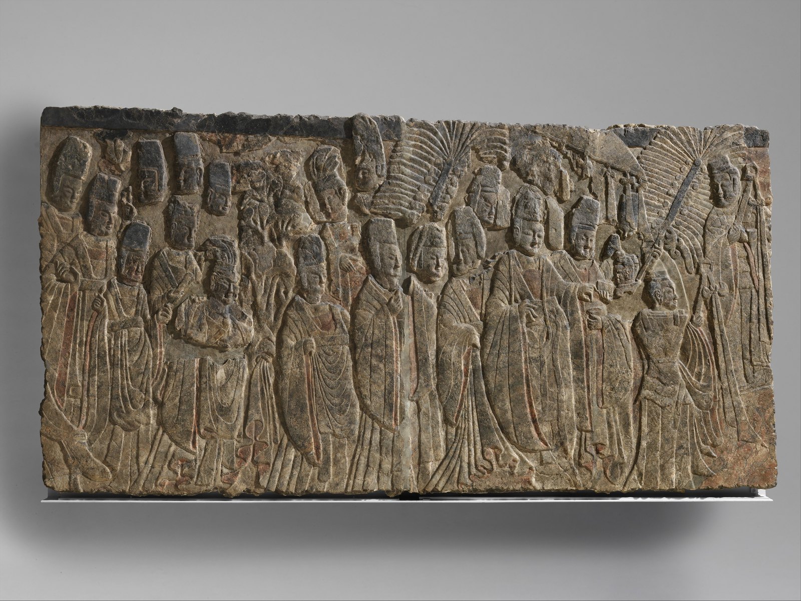 Relieve ancho de piedra caliza con una procesión imperial y acompañantes.