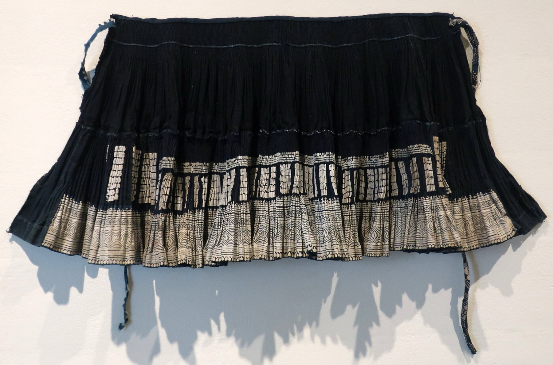 A Miao child’s festival skirt from Guizhou uses cotton, wax-resist indigo and woven construction.