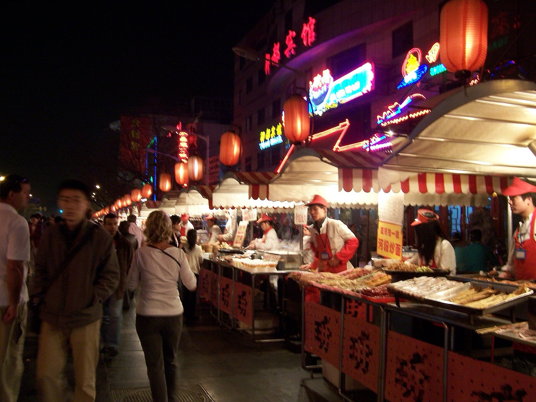 Illuminated stalls and pedestrians animate a Beijing night market in 2006.