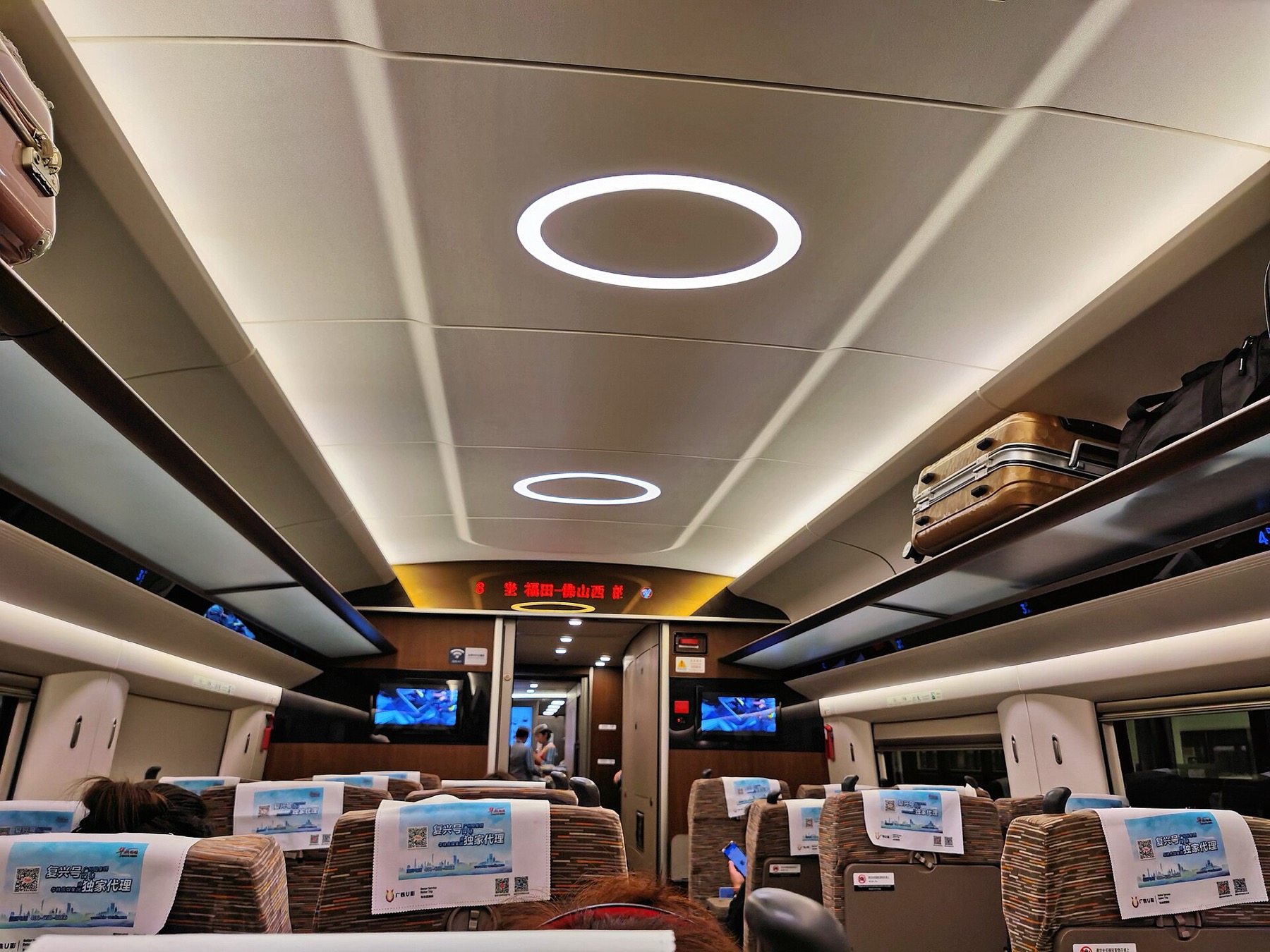 Rows of seats and continuous lighting define the passenger interior of a Fuxing train.