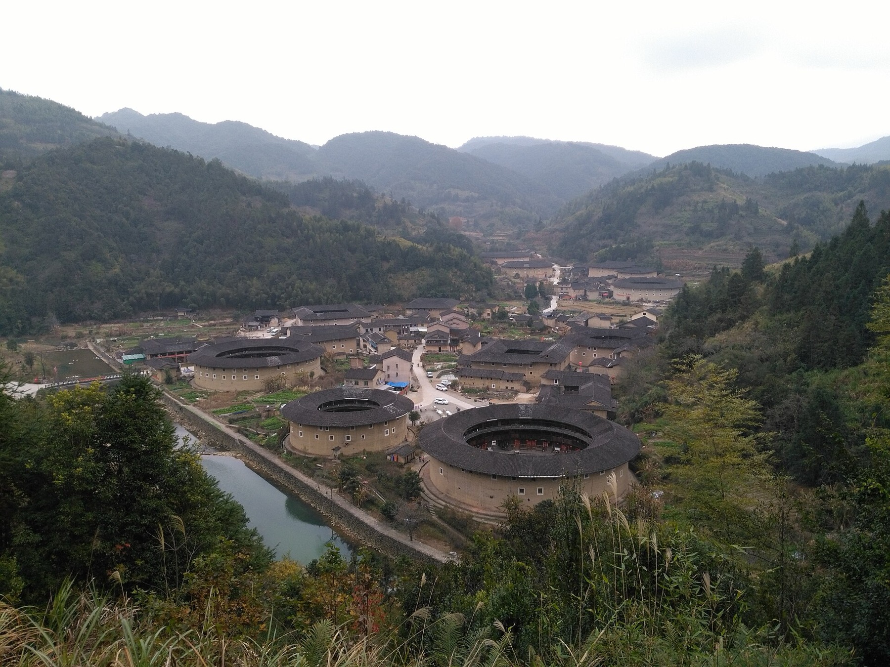 A bird’s-eye view shows circular and square tulou distributed through a Fujian valley.