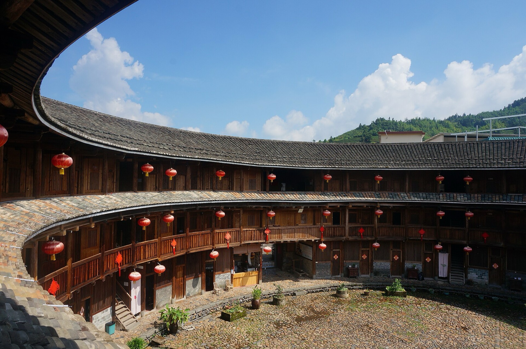 A close architectural view shows the earthen wall and timber structure of a Fujian tulou.